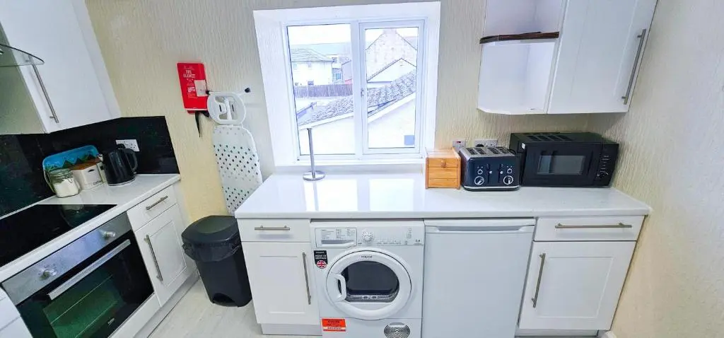 a kitchen with a washing machine and a window at Fraser 2 Bedroom Apartment - Inverness in Inverness