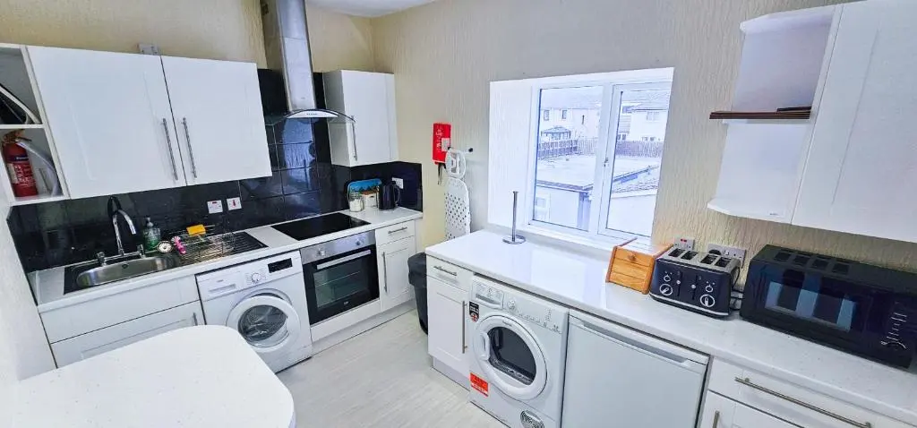 a kitchen with a sink and a washing machine at Fraser 2 Bedroom Apartment - Inverness in Inverness