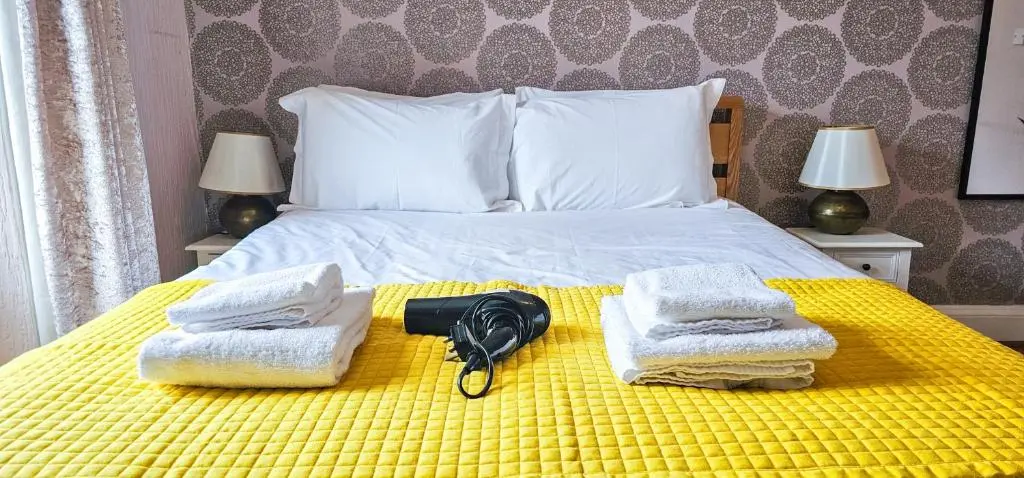 a bedroom with a bed with towels and a camera on it at mySTAYINN Inverness Guest House - Rooms in Inverness