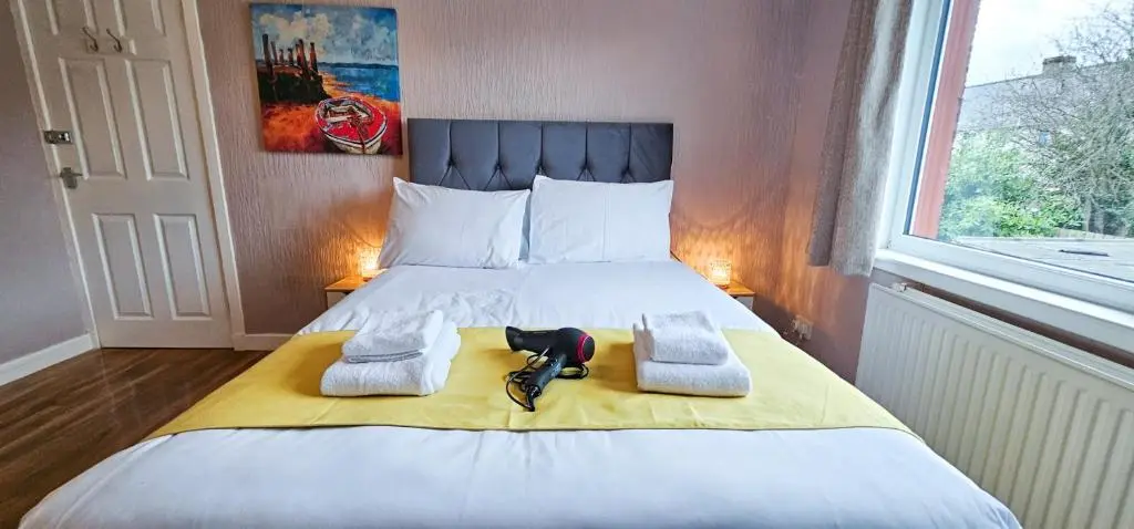 a bedroom with a bed with towels and a window at mySTAYINN Inverness Guest House - Rooms in Inverness