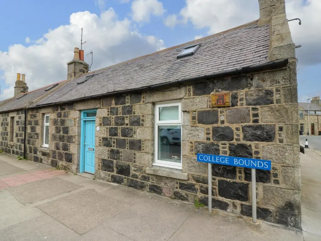 a stone building with a blue door and a sign at 2 College Bounds in Fraserburgh