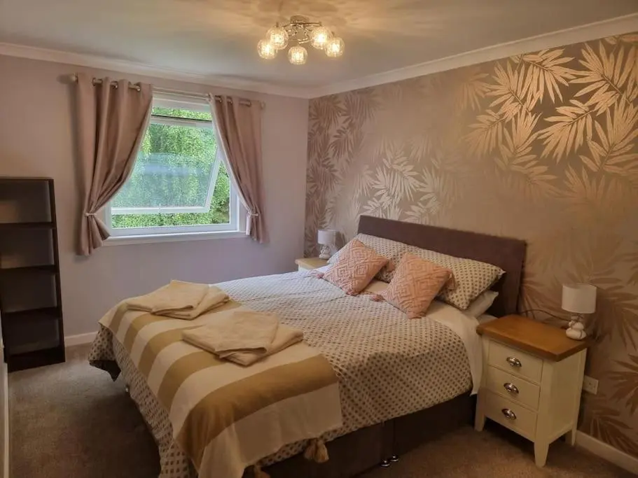 a bedroom with a bed and a window at Rowanlea Cottage in Inverness