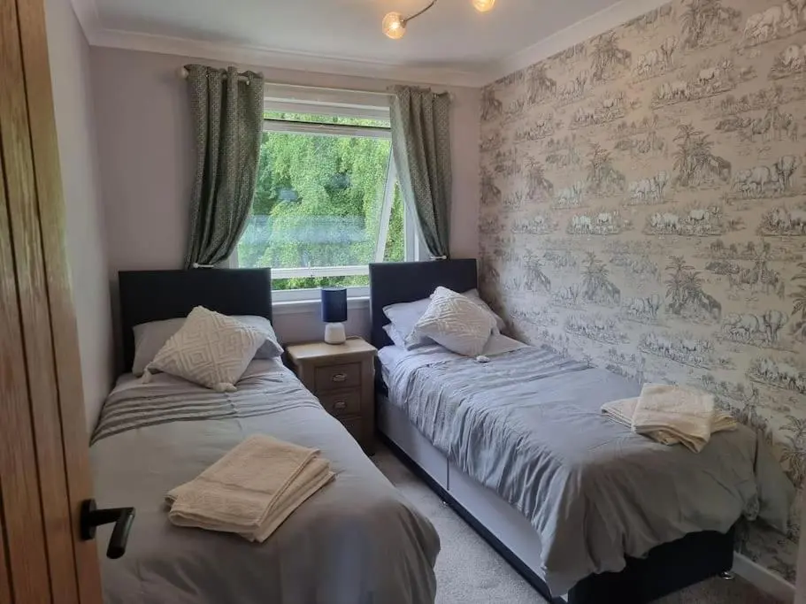 two twin beds in a room with a window at Rowanlea Cottage in Inverness