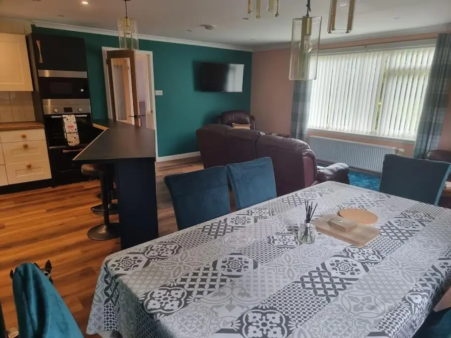 a dining room with a table with a white table cloth at Rowanlea Cottage in Inverness