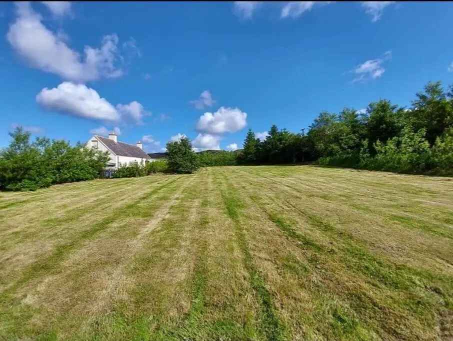 a field of grass with a house in the background at Torran Cottage - Views, Exclusivity & Tranquility in Halkirk