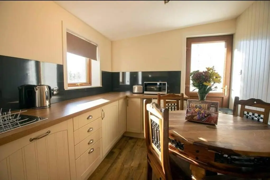a kitchen with a wooden table and a kitchen with a tableablish at Torran Cottage - Views, Exclusivity & Tranquility in Halkirk