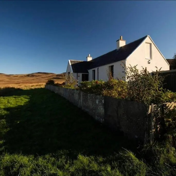 a white house with a fence in front of it at Torran Cottage - Views, Exclusivity & Tranquility in Halkirk