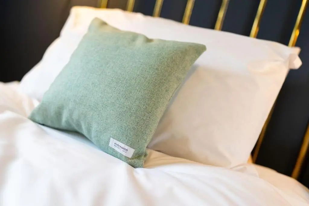 a green pillow on a bed with white pillows at Westerpark Cottage, Pet & Family Friendly Countryside Retreat, Aberdeenshire in Huntly