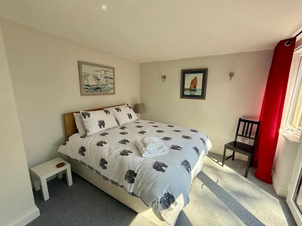 a bedroom with a large bed and a red curtain at Modern Coastal Retreat, 5-Bedroom, 4-Bathroom Home, with Parking in Portsoy in Portsoy