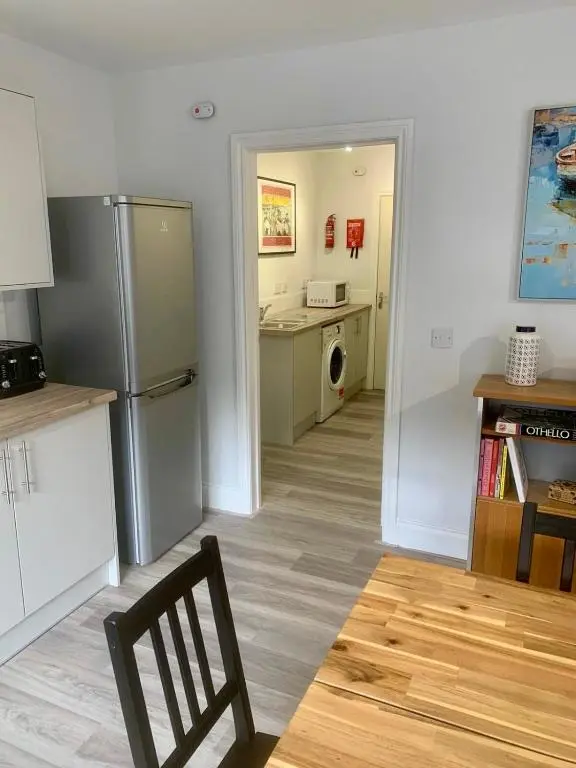 a kitchen with a refrigerator and a table and a chair at Modern Coastal Retreat, 5-Bedroom, 4-Bathroom Home, with Parking in Portsoy in Portsoy