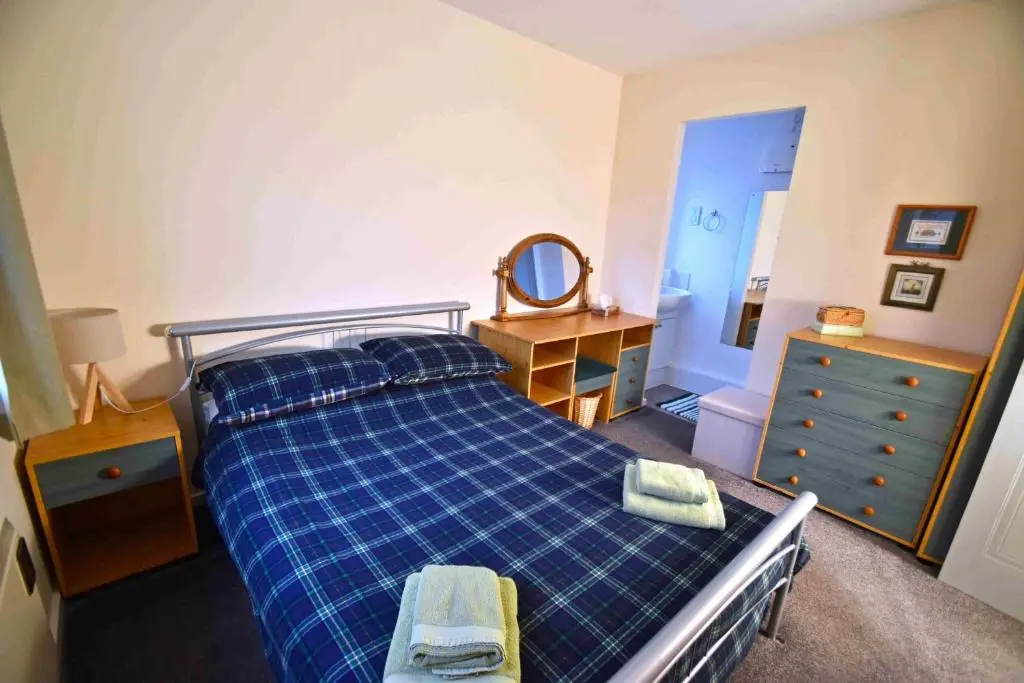 a bedroom with a bed and a dresser and a mirror at Birch View in Aviemore