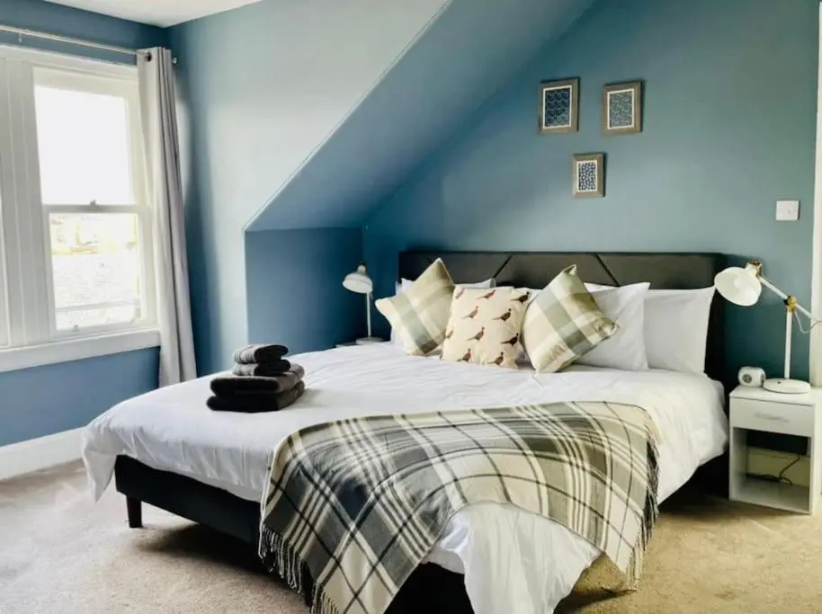 a bedroom with a large bed with blue walls at Charming 3-bedroom maisonnette in Inverness City Centre in Inverness