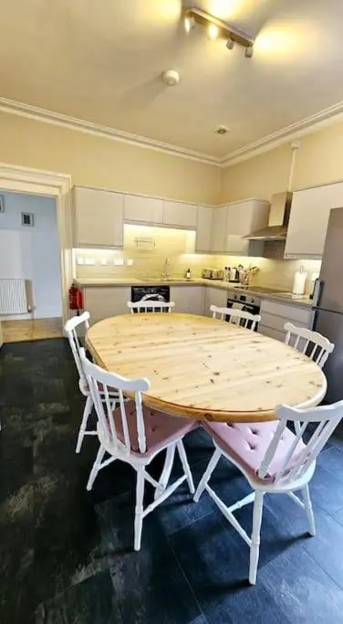 a kitchen with a wooden table and white chairs at Charming 3-bedroom maisonnette in Inverness City Centre in Inverness