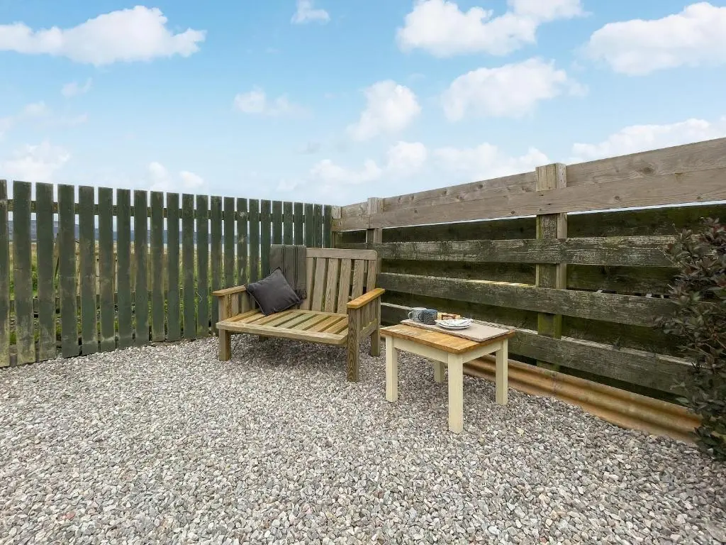 a wooden chair and a table next to a fence at The Wee Belter in Dornoch