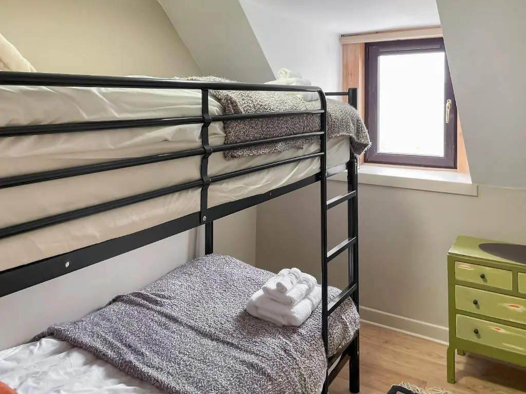 a bedroom with two bunk beds and a window at The Wee Belter in Dornoch