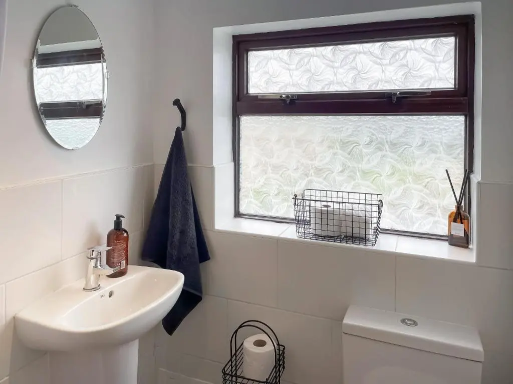 a white bathroom with a sink and a window at The Wee Belter in Dornoch