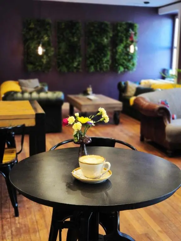 a table with a cup of coffee and a vase with flowers at The Salt house in Golspie