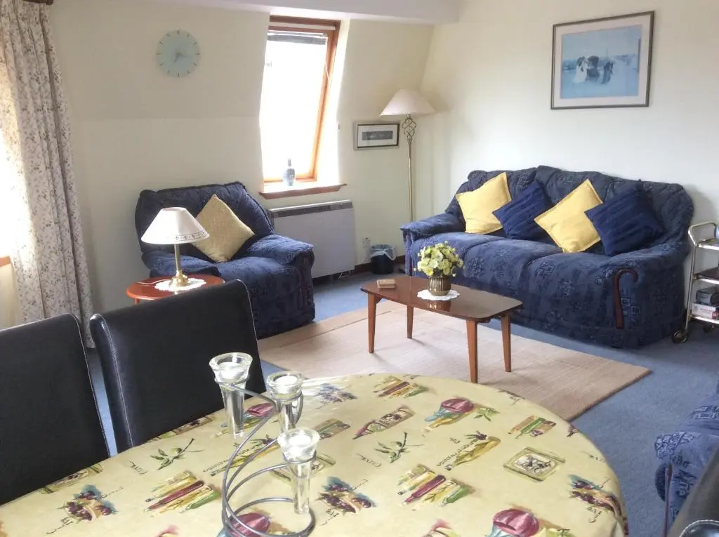 a living room with a blue couch and a table at Connel Court Apartments in Inverness