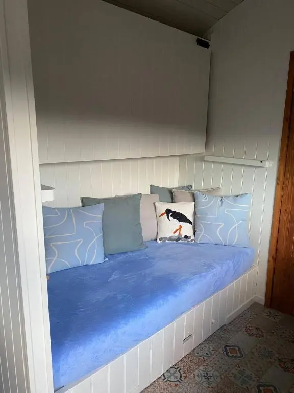 a bed with blue pillows in a room at Ledmacoy Shepherds Huts in Strathdon