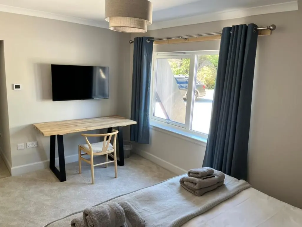 a bedroom with a bed and a desk and a television at Dune House, Golf Road, Dornoch 5x Bedrooms in Dornoch