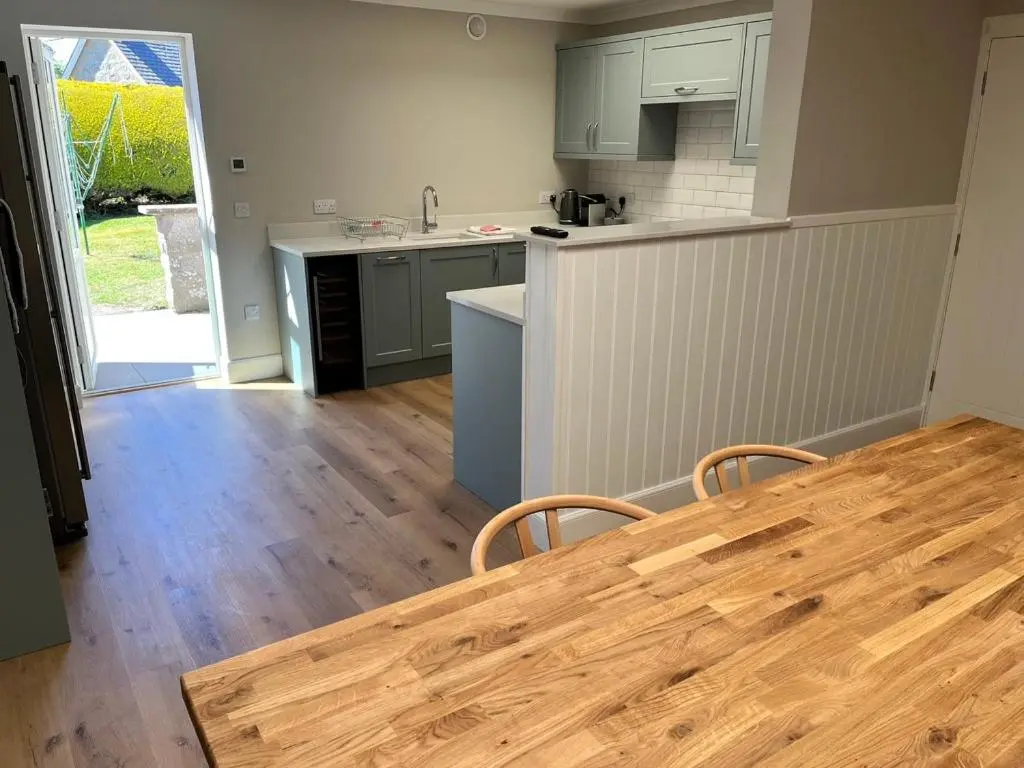 a kitchen with a wooden table and a wooden floor at Dune House, Golf Road, Dornoch 5x Bedrooms in Dornoch