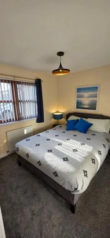 a bedroom with a large bed with blue pillows at Modern Dornoch Apartment in Dornoch