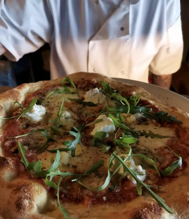 a pizza sitting on top of a plate on a table at Bruadarach 'Visionary, Dreamer' in Dunbeath