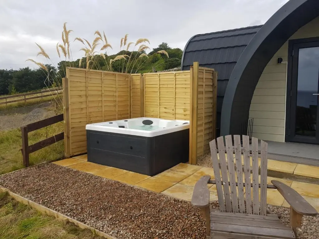 a hot tub and a chair on a patio at Bruadarach 'Visionary, Dreamer' in Dunbeath