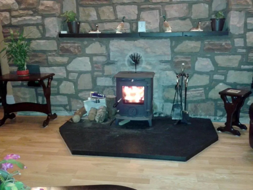 a stone fireplace in a living room with a stove at Ornum House in Beauly