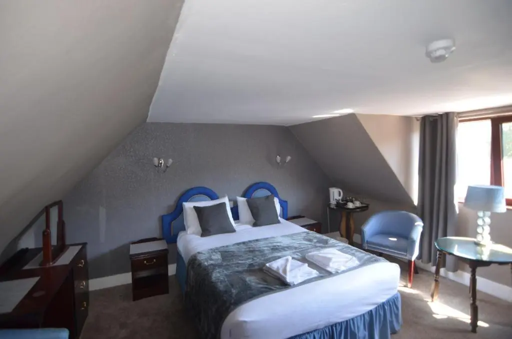 a bedroom with a king sized bed in a attic at Achilty Guest House in Contin