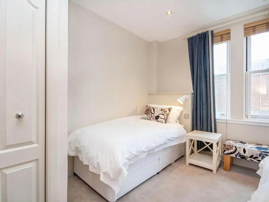 a bedroom with a white bed and a window at Townhouse on the Square, Dornoch in Dornoch