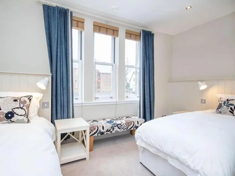 a bedroom with two beds and a window at Townhouse on the Square, Dornoch in Dornoch