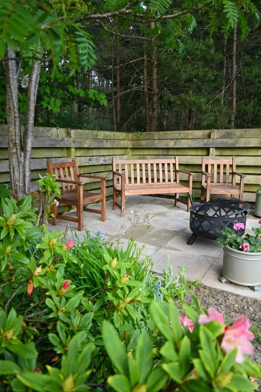 three benches sitting on a patio in a garden at Greenwood - Stunning Scandinavian Style Home in the heart of Ballater Royal Deeside in Ballater