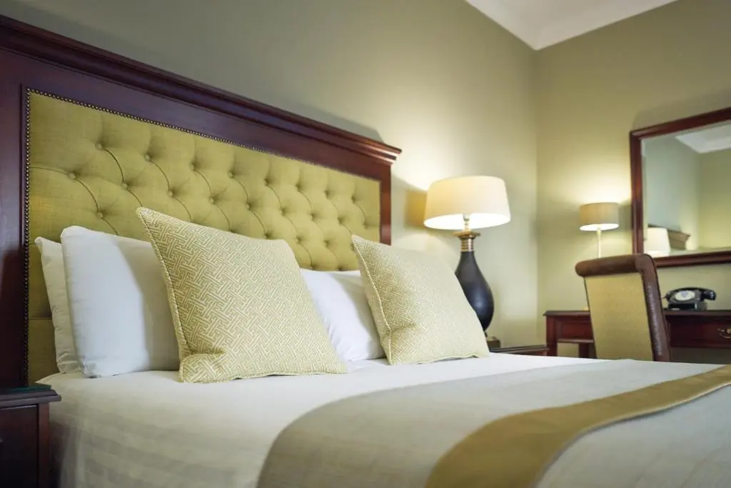 a bedroom with a large bed with a large headboard at Golf View Hotel & Spa in Nairn
