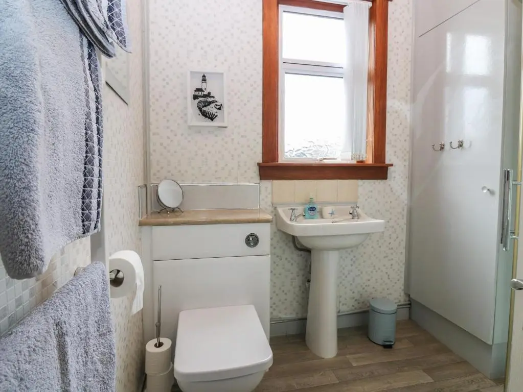 a bathroom with a sink and a toilet and a window at Thain House in Banff