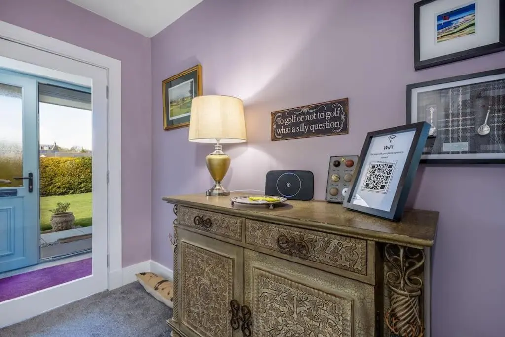 a room with a table with a lamp and a window at Orcadia Sutherland Road Dornoch IV25 3SX in Dornoch