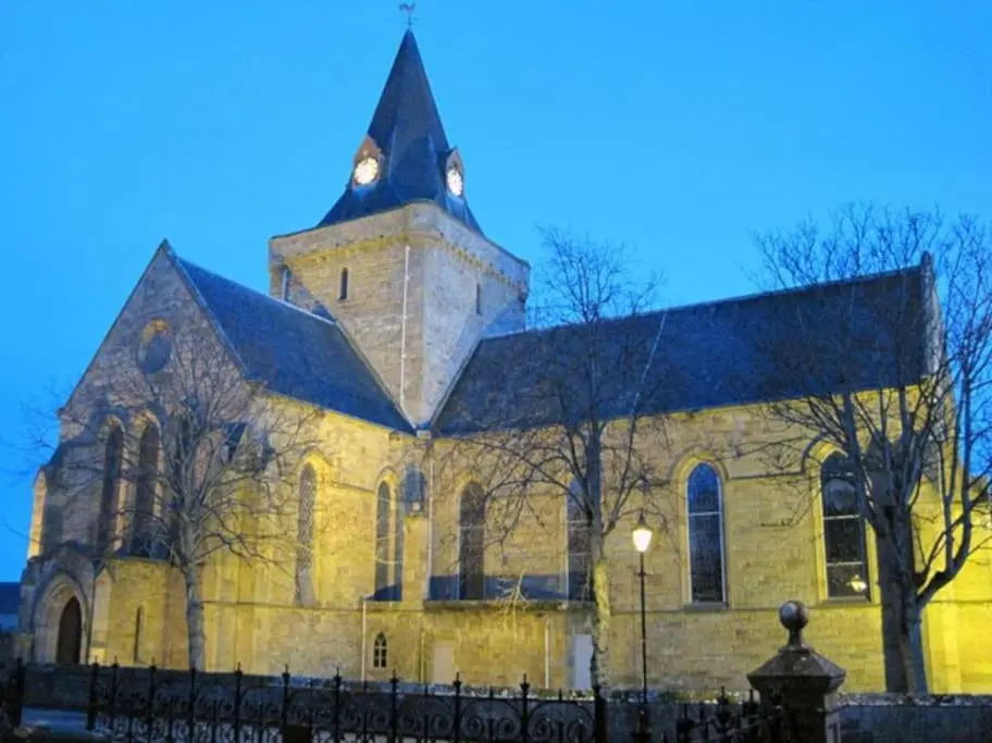a church with a clock tower on top of it at Orcadia Sutherland Road Dornoch IV25 3SX in Dornoch