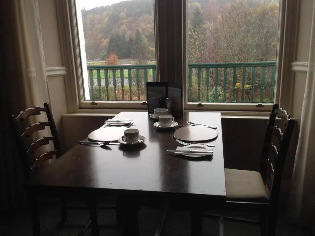 a dining room table with chairs and two windows at Highlander Inn in Craigellachie