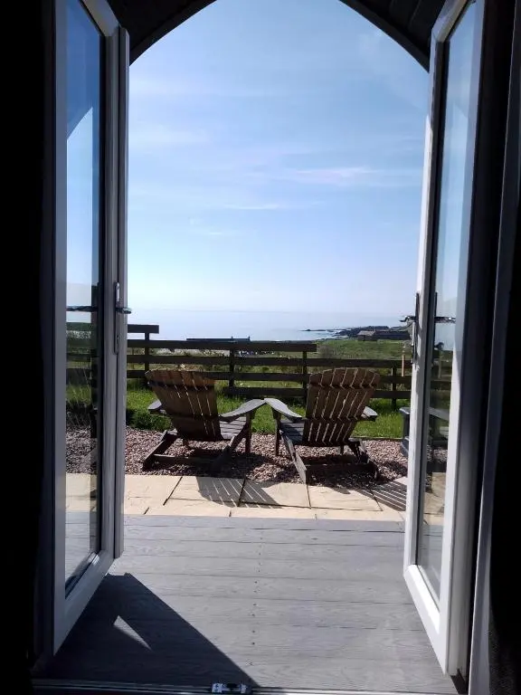 an open door to a patio with a view of the ocean at Camhanaich 'Half light of dawn' in Dunbeath