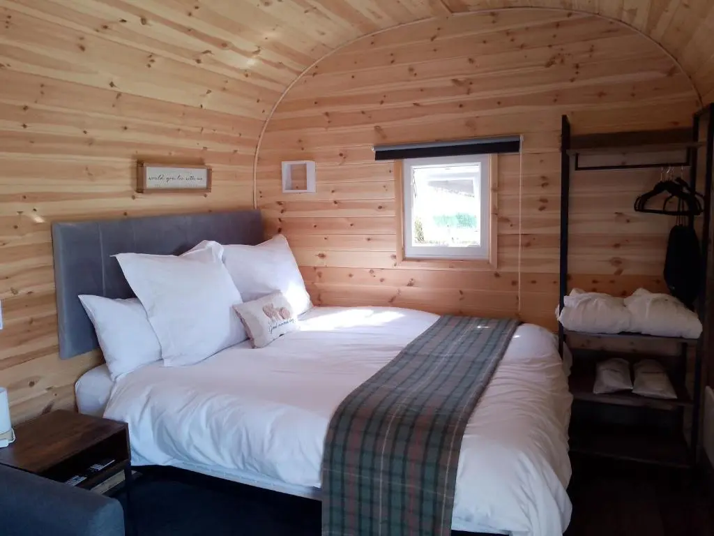 a bedroom with a bed in a wooden cabin at Camhanaich 'Half light of dawn' in Dunbeath