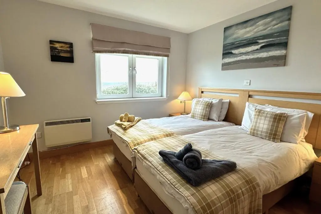 a bedroom with a bed with a black towel on it at No2 The Links Apartment, Brora in Brora