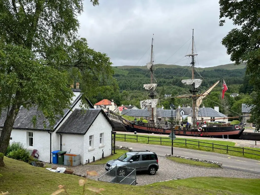 a car parked in front of a large boat at Ness View Cottage in Fort Augustus