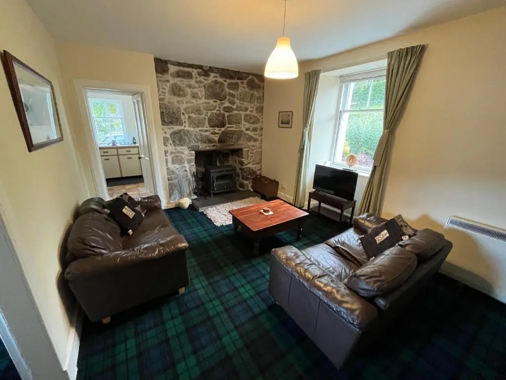 a living room with two couches and a fireplace at Ness View Cottage in Fort Augustus