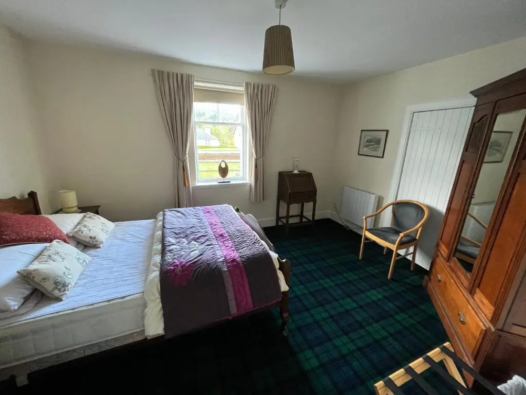 a bedroom with a bed and a window and a chair at Ness View Cottage in Fort Augustus