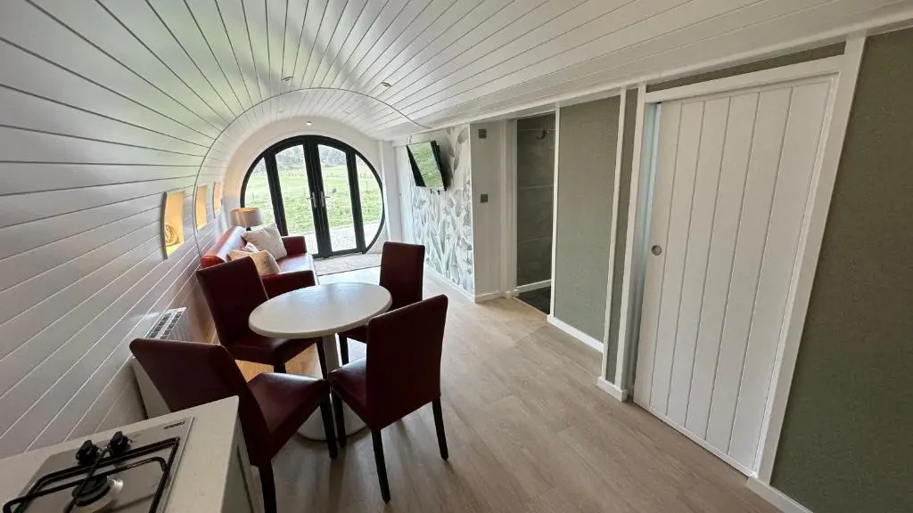 a room with a table and chairs and a door at Juniper Lodges in Inverness