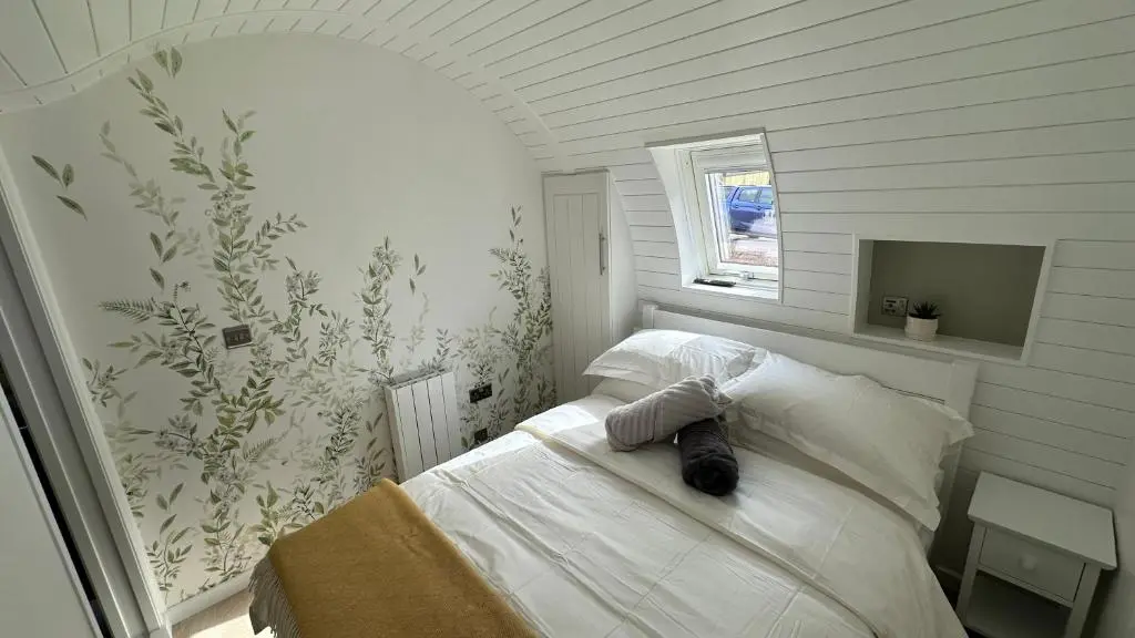 a bedroom with a bed with white sheets and a window at Juniper Lodges in Inverness