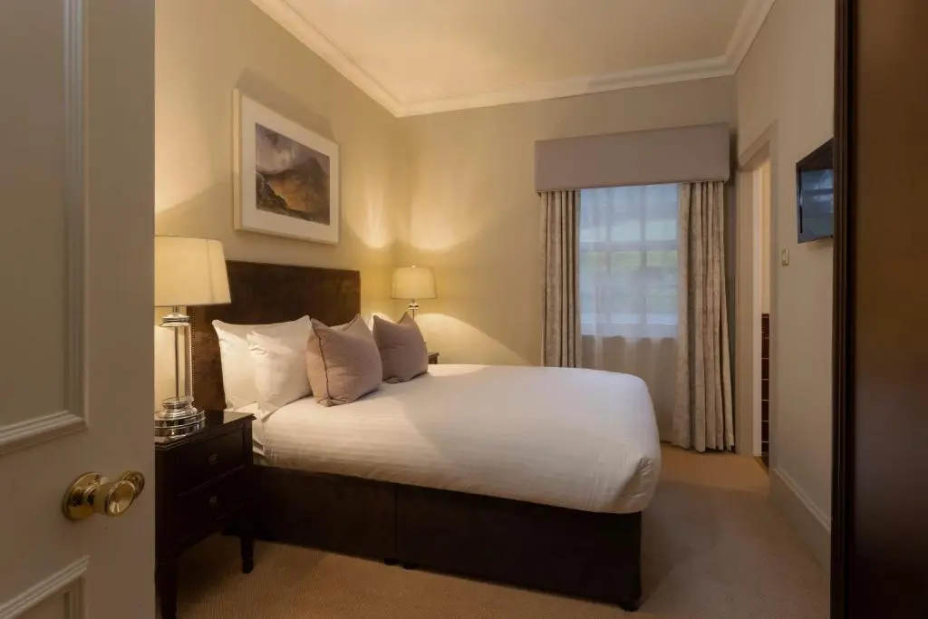a bedroom with a bed with white sheets and a window at Thainstone House in Inverurie