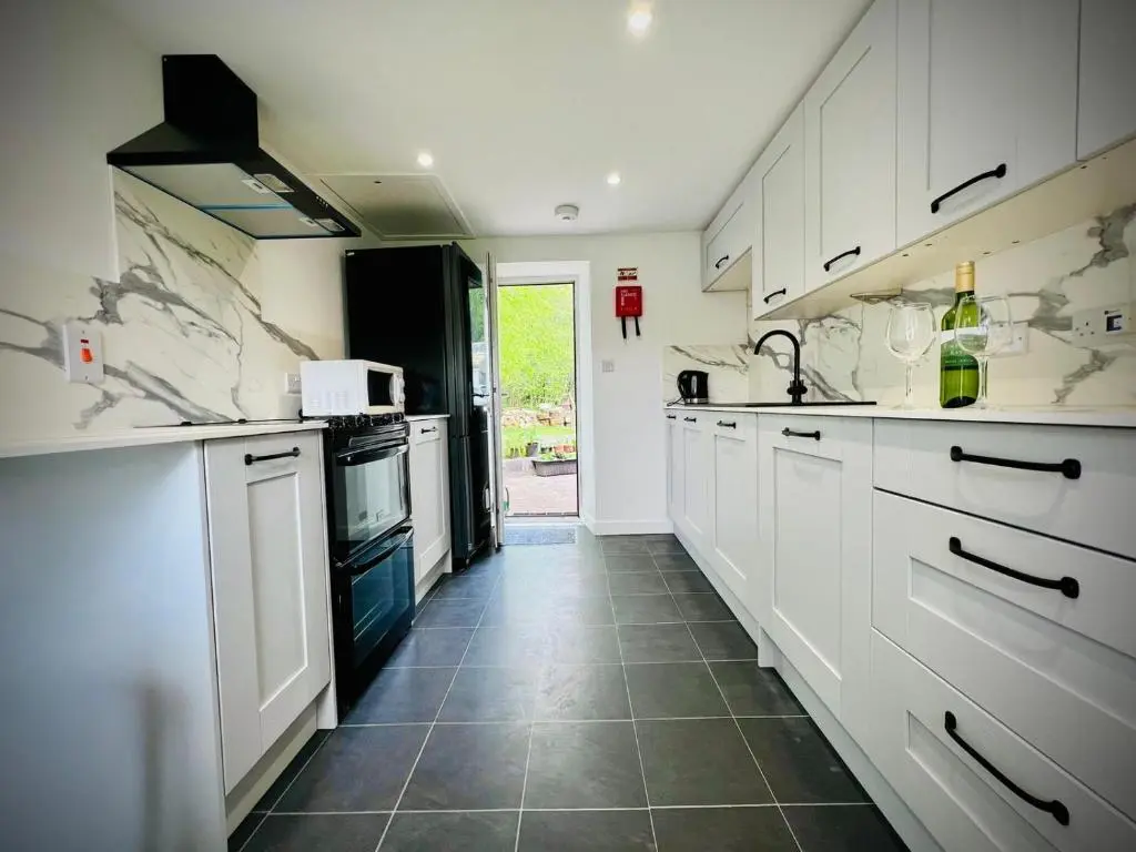 a kitchen with white cabinets and a tile floor at Cosy Country House in Deeside in Finzean