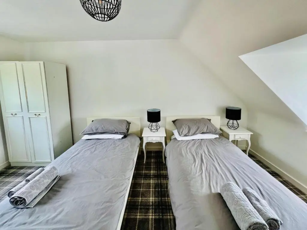 two beds in a room with two tables at Cosy Country House in Deeside in Finzean