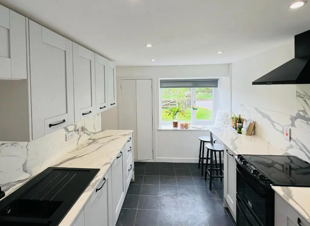 a white kitchen with white cabinets and a window at Cosy Country House in Deeside in Finzean